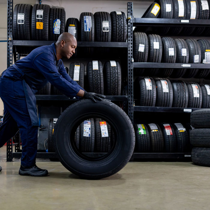 mechanic wheeling tire through shop