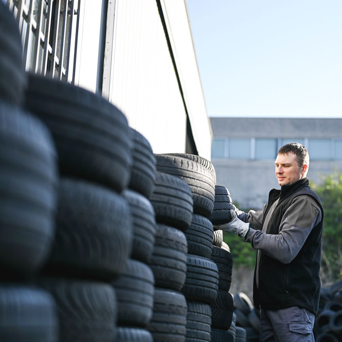man looking at stacks of tires outside shop