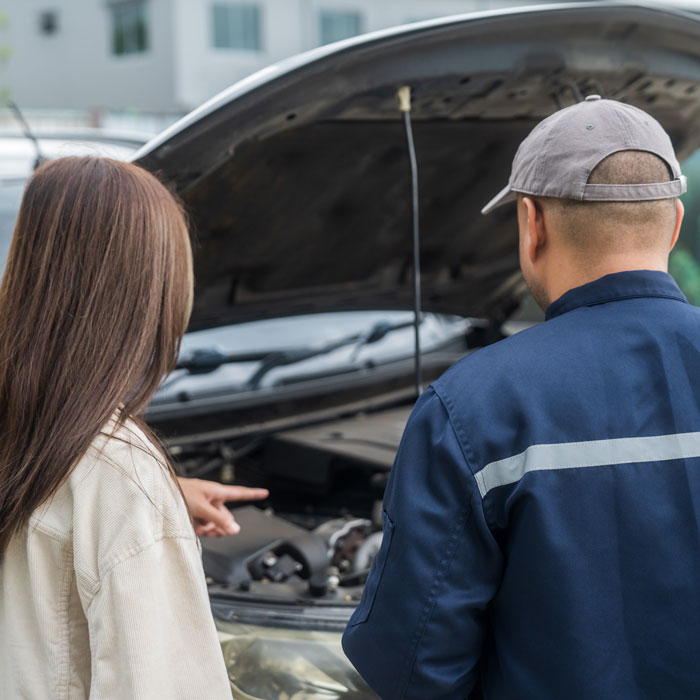 mechanic looking at broken down car