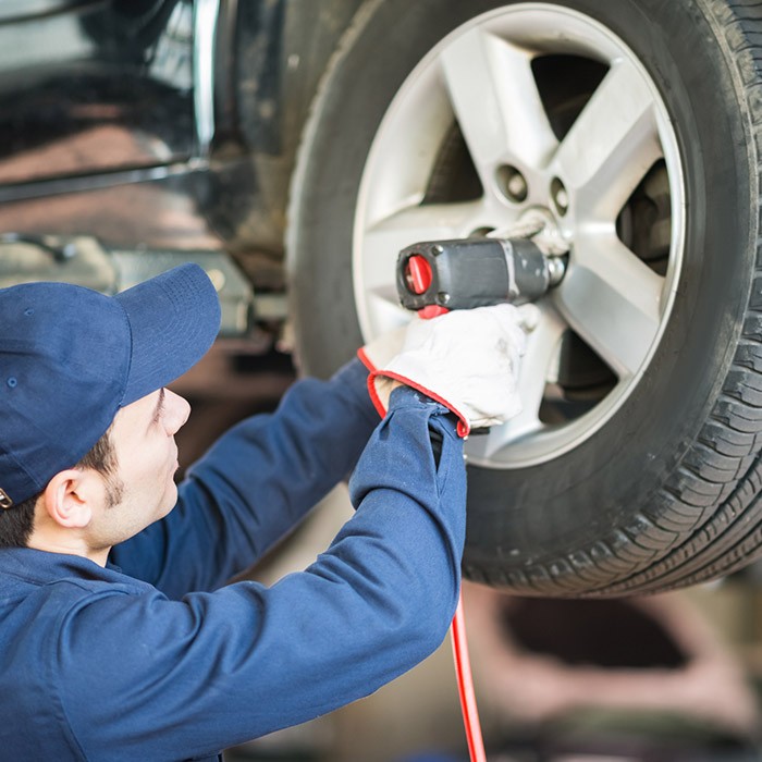 A mechanic is inspecting a car tire in a professional garage in Timonium, MD
